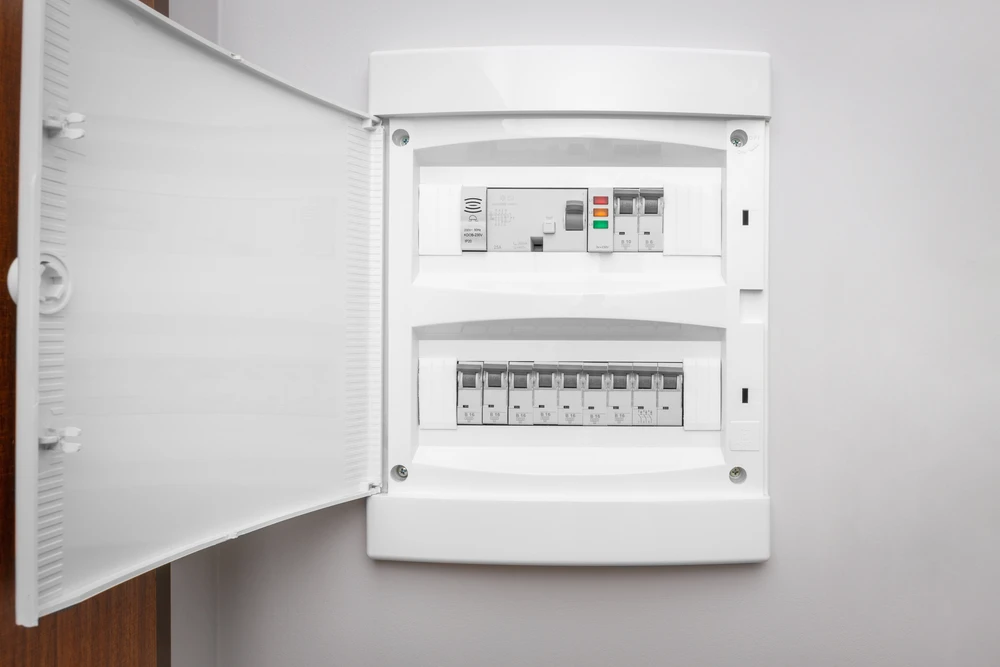 Intérieur résidentiel avec tableau électrique ouvert fixé au mur blanc