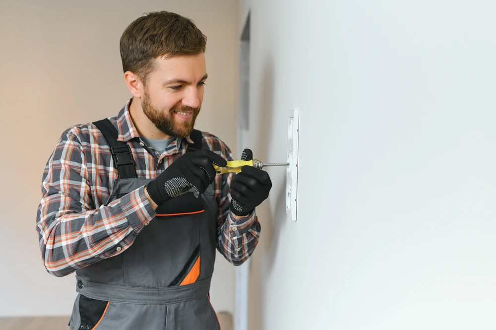 L'électricien installe le cadre décoratif sur les prises électriques et TV
