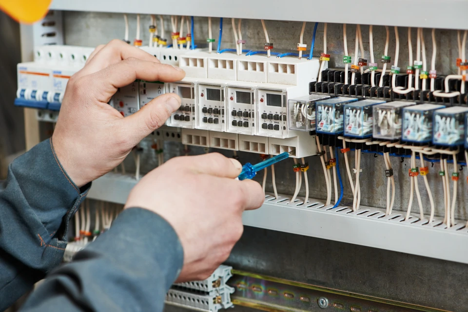 Intérieur d'armoire électrique avec technicien effectuant maintenance sur tableau de distribution