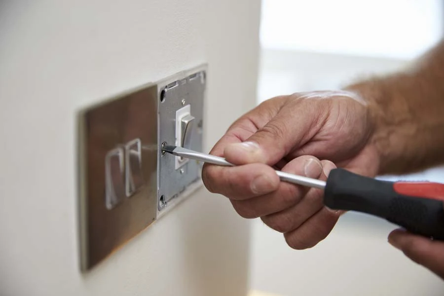 Scène d'intérieur montrant un électricien installant un interrupteur mural