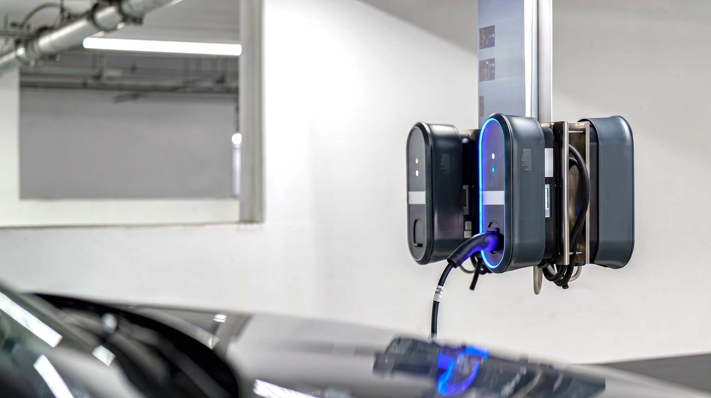 Scène extérieure de recharge d'un véhicule électrique blanc sur parking avec sol carrelé bleu et lignes oranges