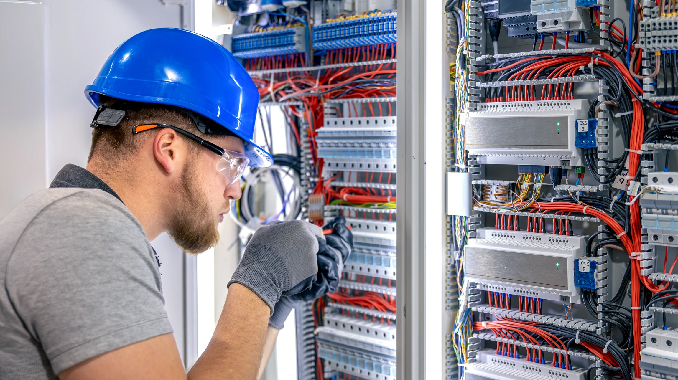 &Eacute;lectricien en combinaison bleue et casque orange travaillant sur installation &eacute;lectrique murale